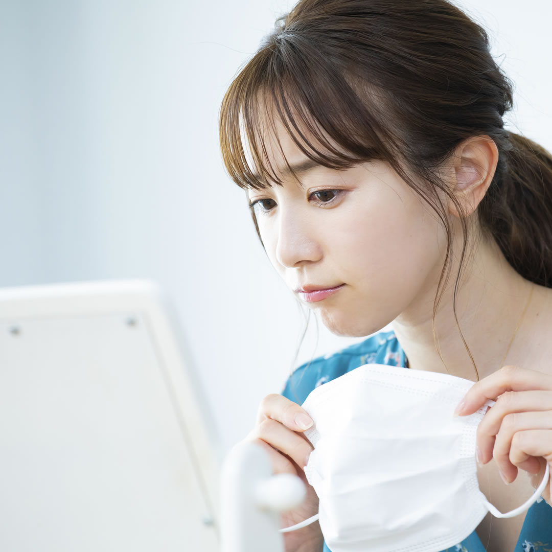 鏡を見てほうれい線を確認している女性